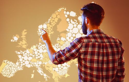 Immagine di un uomo in piedi davanti a una mappa digitale e interattiva dell'Europa