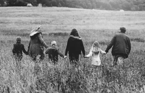 Foto in bianco e nero di una famiglia ripresa di spalle mentre passeggia in un campo