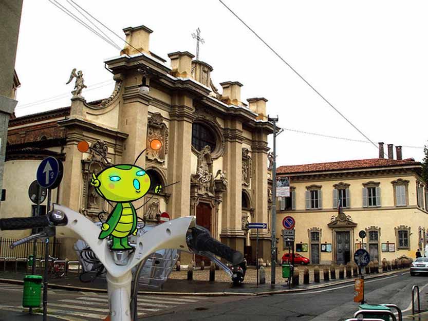 Manubrio di bicicletta con disegnato un grillo (in primo piano) con un edificio sullo sfondo