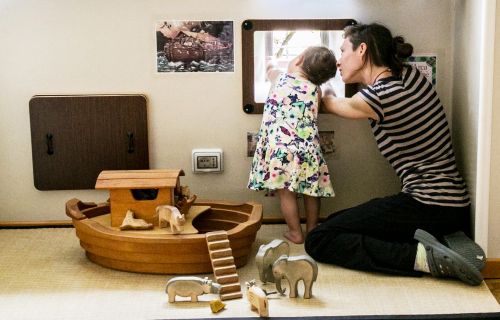 Foto di un'educatrice e una bambina prese di spalle all'interno del nido Bicocca