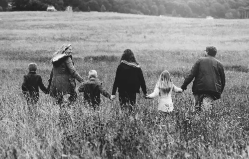 Foto in bianco e nero di una famiglia ripresa di spalle mentre passeggia in un campo