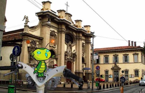 Manubrio di bicicletta con disegnato un grillo (in primo piano) con un edificio sullo sfondo